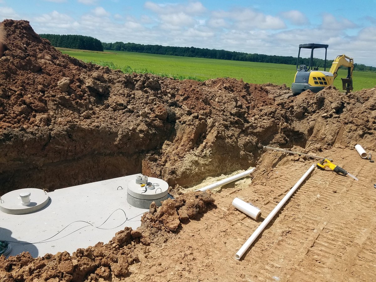 Concrete septic holding tanks being lowered into an excavated pit for a new home construction in Kaufman County