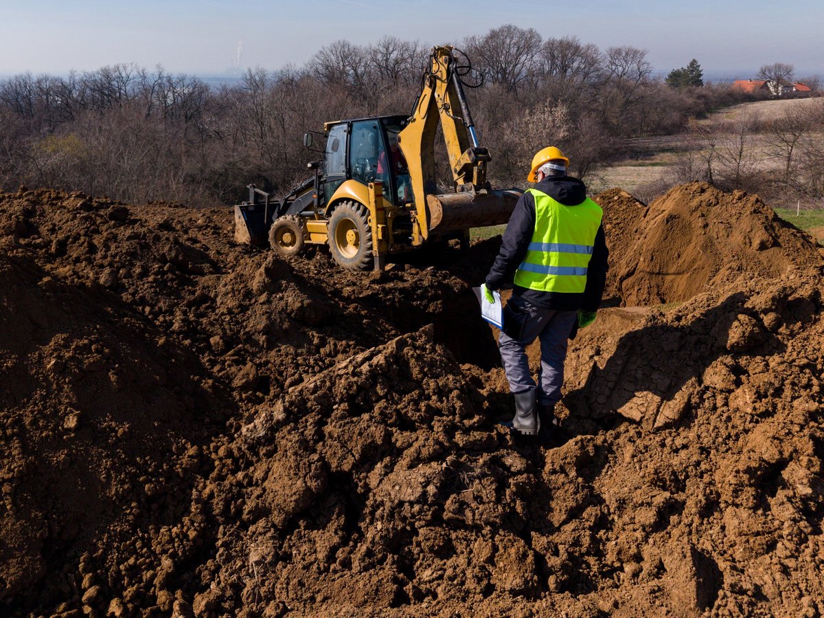 Septic installation crew directing excavator during grading at a Texas acreage jobsite at dusk